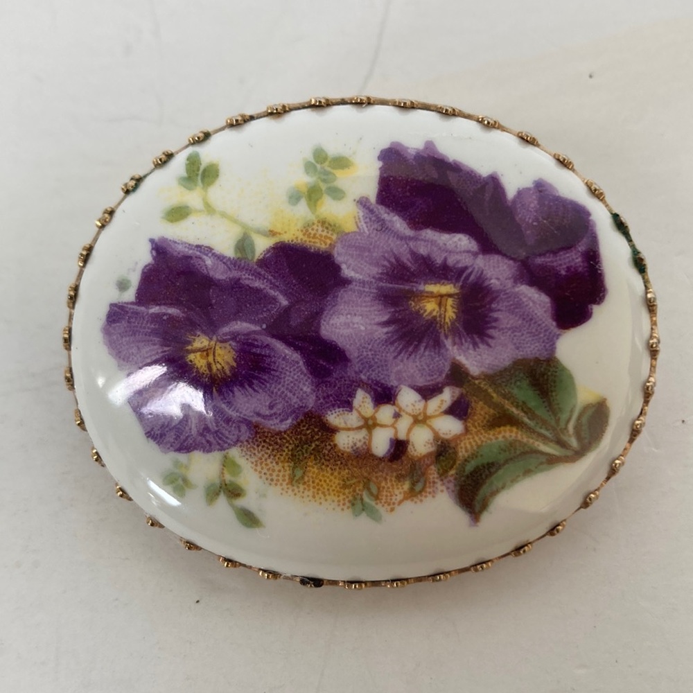 Z125- Vintage brooch that has a gold colored edge with a floral print.